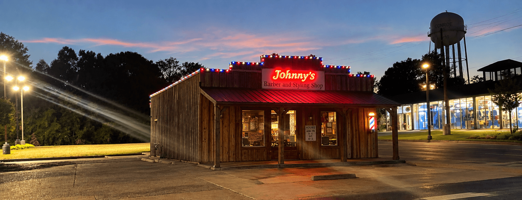 Johnny's Barber and Styling Shop at dusk, neon sign lit above the porch
